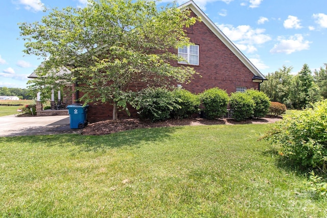 view of home's exterior with brick siding and a lawn