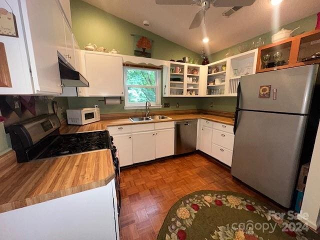 kitchen featuring dark parquet floors, sink, vaulted ceiling, white cabinetry, and stainless steel appliances