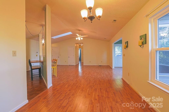 unfurnished room featuring lofted ceiling, plenty of natural light, baseboards, and wood finished floors