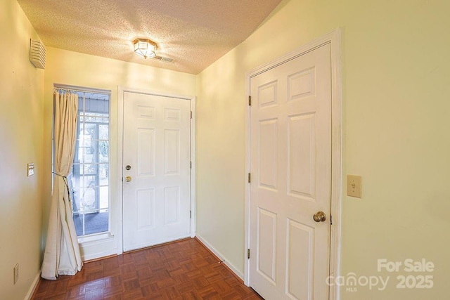 entryway featuring a textured ceiling and dark parquet floors