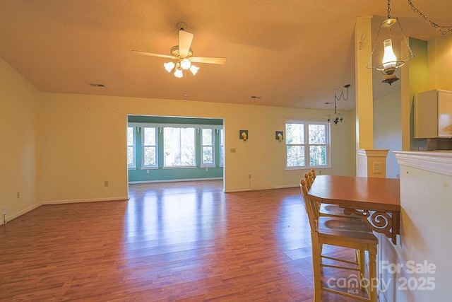 unfurnished living room featuring a ceiling fan, wood finished floors, visible vents, and a healthy amount of sunlight