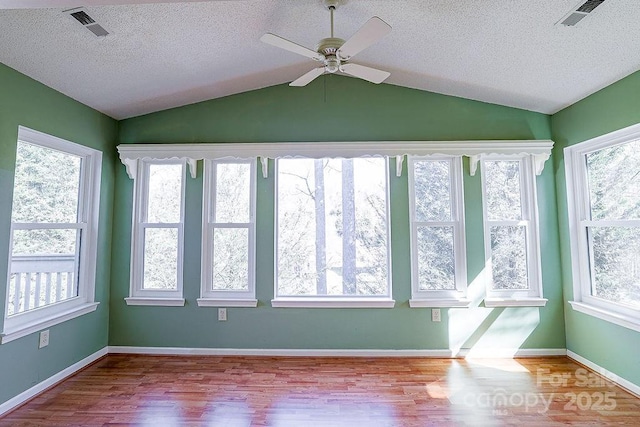 unfurnished sunroom featuring lofted ceiling, plenty of natural light, and visible vents