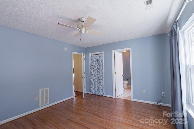 spare room featuring a textured ceiling, light wood finished floors, visible vents, and baseboards