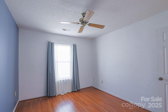 unfurnished room with baseboards, visible vents, a ceiling fan, a textured ceiling, and light wood-type flooring