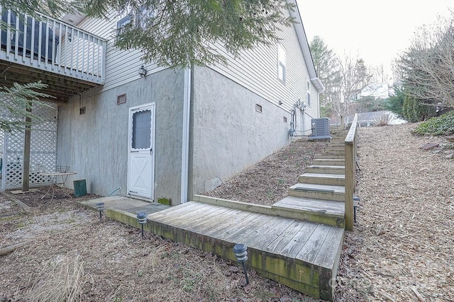 view of side of home featuring stairs, central AC unit, and stucco siding