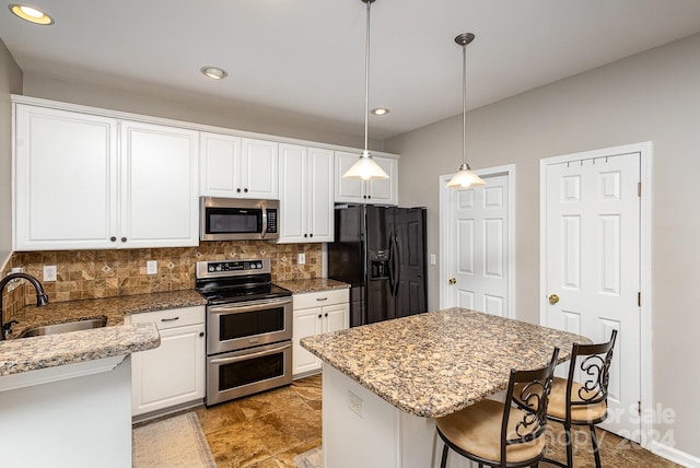 kitchen with stainless steel appliances, sink, decorative light fixtures, and white cabinets