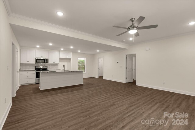 kitchen with white cabinets, appliances with stainless steel finishes, sink, backsplash, and a kitchen island with sink