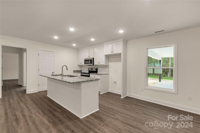 kitchen featuring white cabinetry, stainless steel appliances, a kitchen island with sink, light stone countertops, and sink