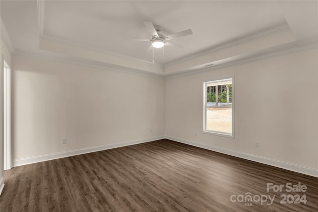 empty room featuring dark wood-type flooring, ornamental molding, a raised ceiling, and ceiling fan