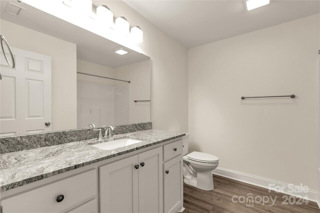 bathroom featuring toilet, a shower, hardwood / wood-style flooring, and vanity