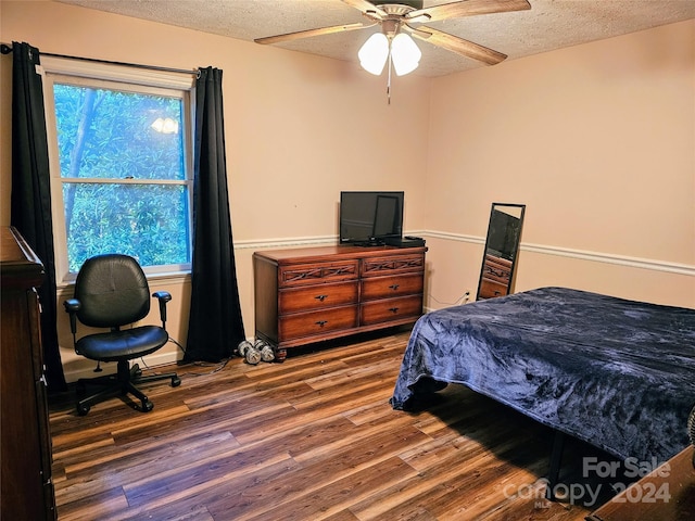 bedroom with a textured ceiling, ceiling fan, and dark hardwood / wood-style flooring