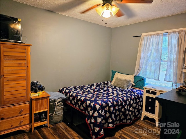 bedroom with ceiling fan, a textured ceiling, and dark hardwood / wood-style flooring