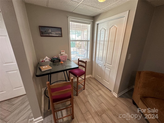 dining area with a paneled ceiling and light hardwood / wood-style floors