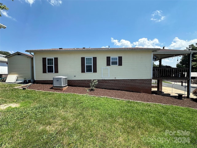 rear view of property featuring a lawn and central air condition unit