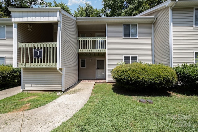 view of front of property featuring a balcony and a front yard