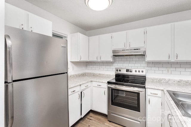 kitchen featuring stainless steel appliances, decorative backsplash, light wood-type flooring, white cabinets, and sink