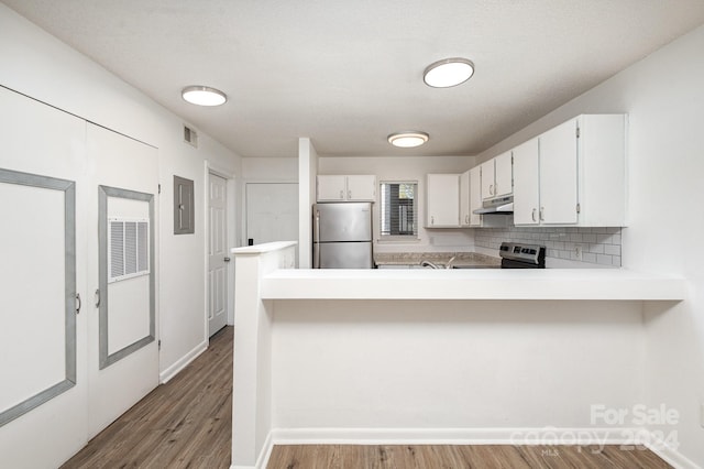 kitchen with electric panel, kitchen peninsula, decorative backsplash, white cabinetry, and appliances with stainless steel finishes