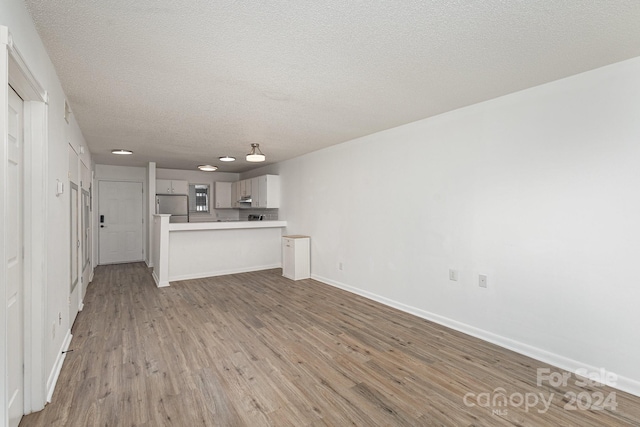 unfurnished living room featuring a textured ceiling and light hardwood / wood-style flooring