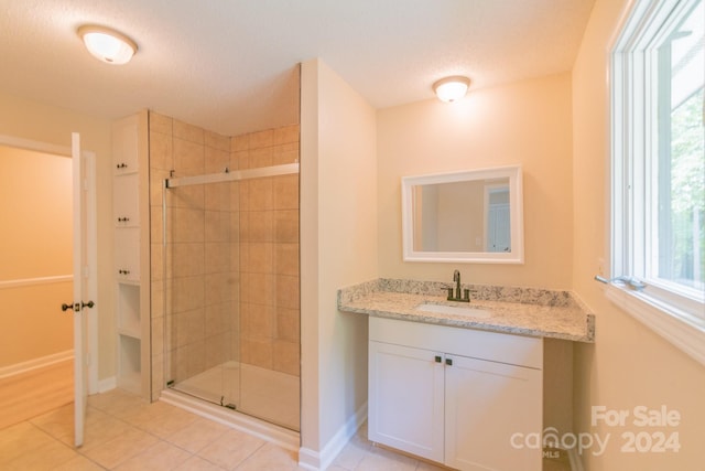 bathroom with a shower with shower door, vanity, tile patterned flooring, and a textured ceiling