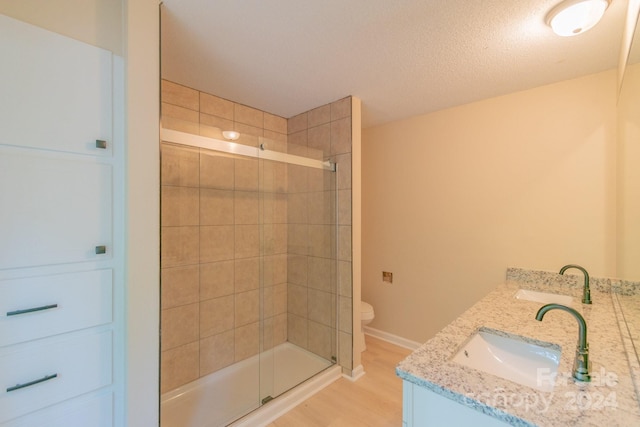 bathroom with toilet, vanity, a shower with shower door, and hardwood / wood-style flooring