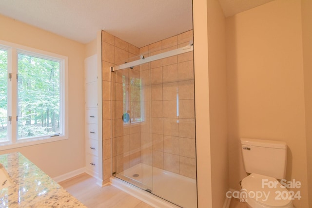 bathroom featuring hardwood / wood-style floors, toilet, and an enclosed shower