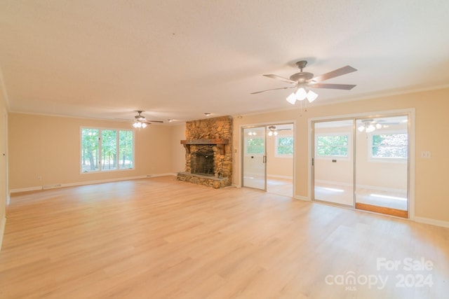 unfurnished living room with ceiling fan, crown molding, a stone fireplace, and light hardwood / wood-style flooring