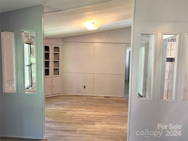 hallway featuring light hardwood / wood-style floors and lofted ceiling