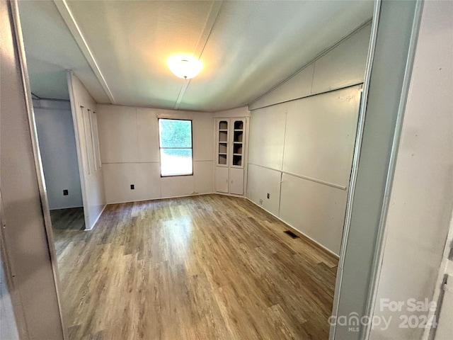 unfurnished bedroom with wood-type flooring and vaulted ceiling