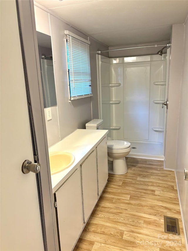 bathroom with a shower, vanity, hardwood / wood-style flooring, and toilet