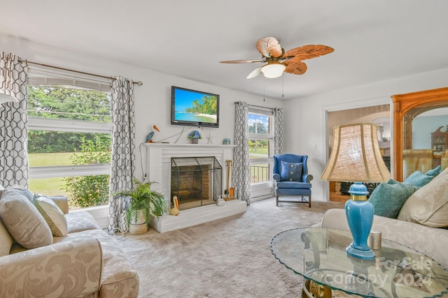 carpeted living room featuring a brick fireplace and ceiling fan