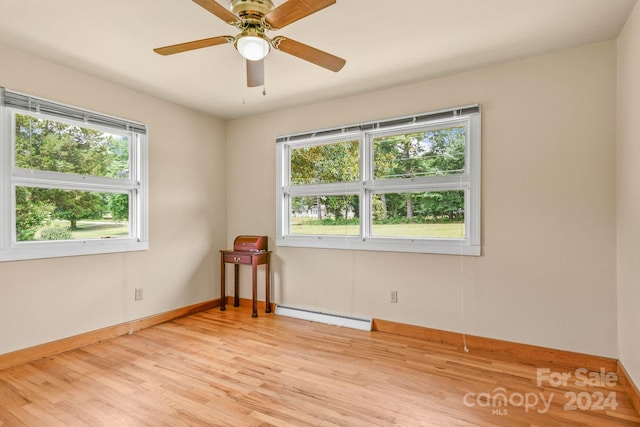 unfurnished room featuring ceiling fan, a baseboard heating unit, light hardwood / wood-style flooring, and a healthy amount of sunlight