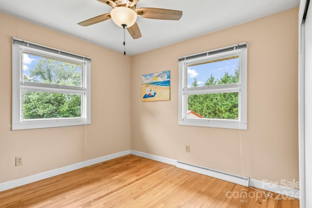 empty room featuring ceiling fan, a baseboard heating unit, plenty of natural light, and light hardwood / wood-style flooring