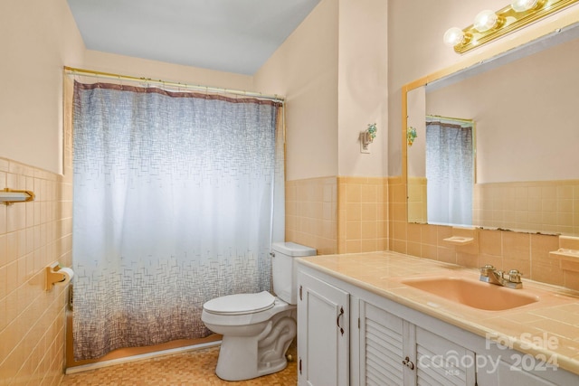 bathroom featuring toilet, tile walls, and vanity