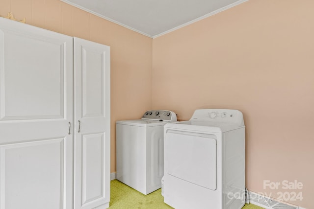 washroom with cabinets, crown molding, and washing machine and dryer