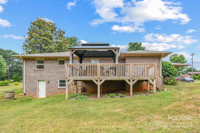 rear view of property featuring a deck, a gazebo, and a lawn