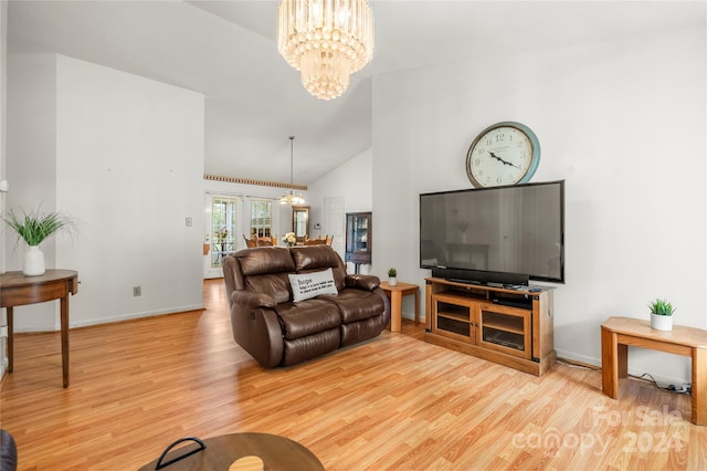 living room with a notable chandelier, light wood-type flooring, and high vaulted ceiling