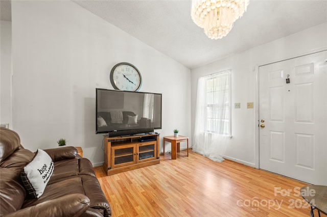 living room featuring an inviting chandelier, wood-type flooring, and vaulted ceiling