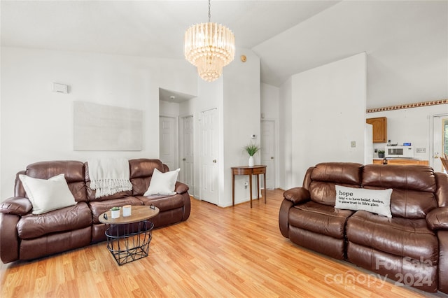 living room with light hardwood / wood-style floors, vaulted ceiling, and a chandelier