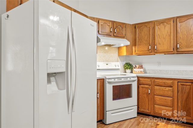 kitchen featuring light hardwood / wood-style flooring, tasteful backsplash, and white appliances