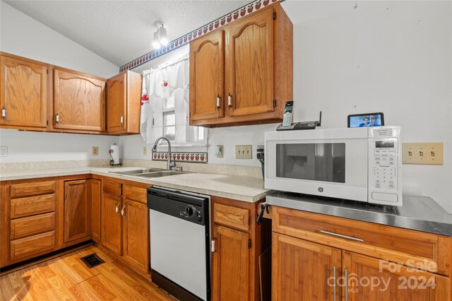 kitchen featuring light hardwood / wood-style floors, white appliances, a textured ceiling, lofted ceiling, and sink