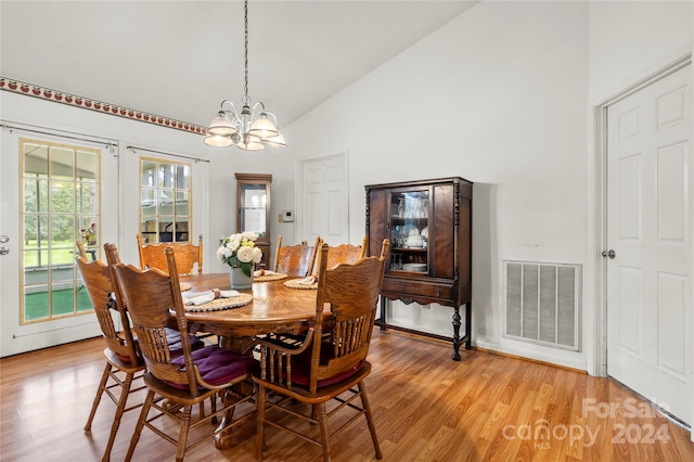 dining room with a notable chandelier, light hardwood / wood-style flooring, high vaulted ceiling, and a healthy amount of sunlight