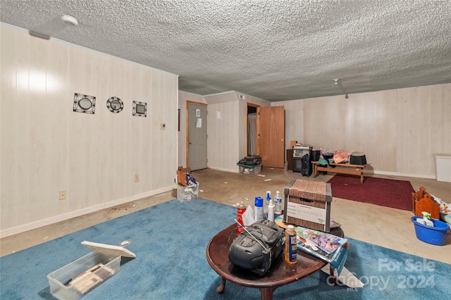 interior space with a textured ceiling, wood walls, and concrete flooring