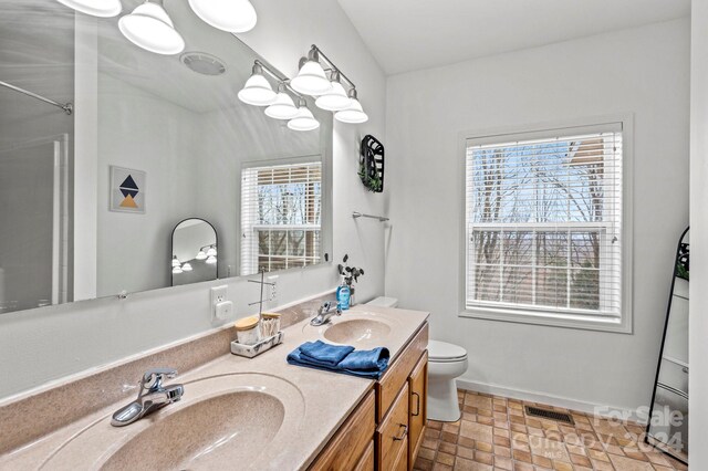 bathroom with vanity, a healthy amount of sunlight, toilet, and vaulted ceiling