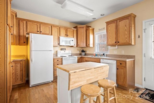 kitchen with white appliances, sink, and light hardwood / wood-style flooring