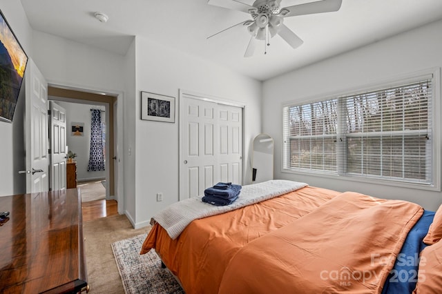 carpeted bedroom featuring ceiling fan and a closet