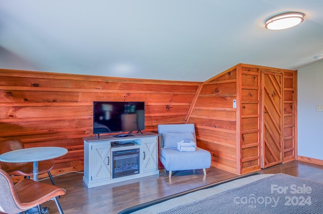 sitting room with vaulted ceiling, dark hardwood / wood-style floors, and wood walls