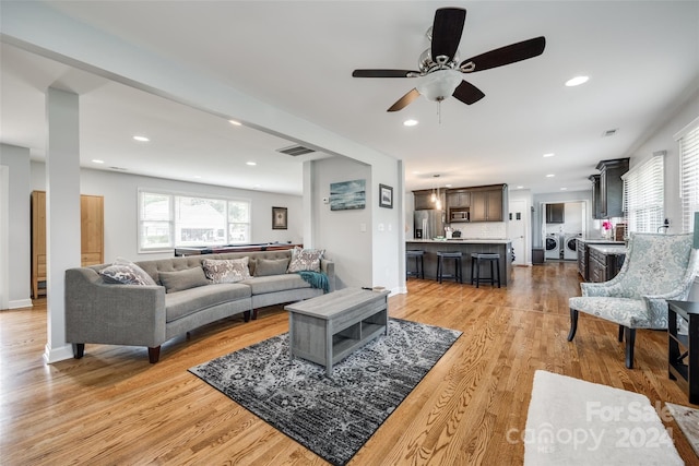 living room featuring ceiling fan, light wood-type flooring, and washing machine and clothes dryer