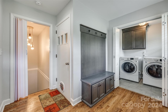 laundry area with cabinets, light wood-type flooring, and washing machine and clothes dryer