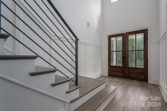 entryway with hardwood / wood-style flooring, a high ceiling, and french doors