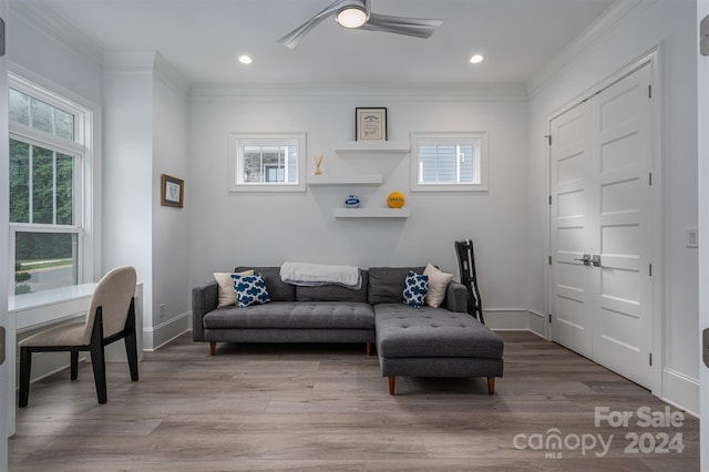 living room featuring crown molding, a healthy amount of sunlight, and light wood-type flooring